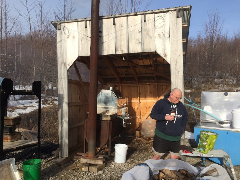 man in front of wooden shed used for maple syrup production